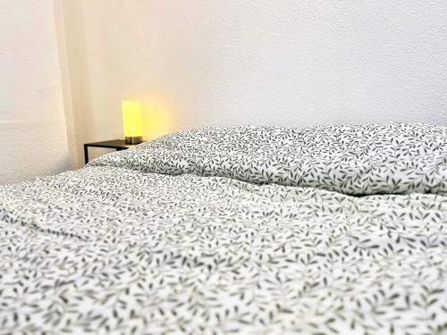 a bed with a black and white comforter and a lamp at L'Antique - Cocon, Centre Historique, Wifi , 4 lits, 6 personnes in Istres
