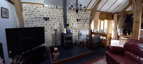 un salon avec une télévision et un mur en pierre dans l'établissement La Grange, à Saint-Agnant-près-Crocq