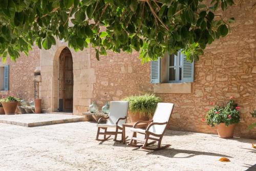 two chairs and a table in front of a building at Predi Son Jaumell Hotel Rural in Capdepera