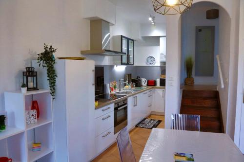 une cuisine avec des armoires blanches et une table et une salle à manger dans l'établissement Les Templiers, à Dole