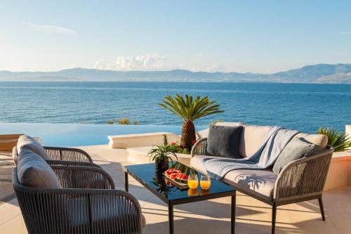 a patio with chairs and a table with a view of the water at La Villa - BEACHFRONT - INFINITY HEATED POOL - NEW in Sutivan