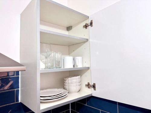 a kitchen with white cabinets and blue tiles at Comfy Studio 30min to Central London in London