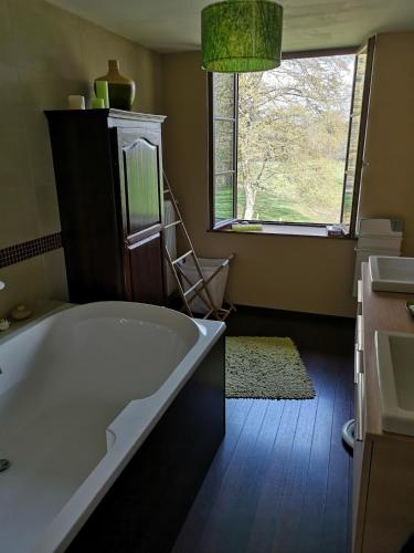 une salle de bain avec une grande baignoire et une fenêtre dans l'établissement La Houssière Maison à la campagne, à La Houssière