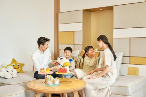 a family sitting in a living room with a table at JW Marriott Jeju Resort & Spa in Seogwipo