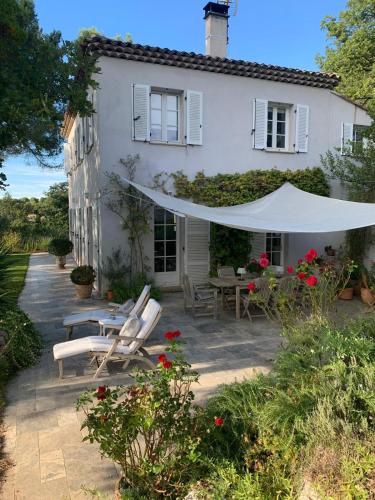 Cette maison blanche dispose d'une terrasse avec des chaises et un parasol. dans l'établissement Lou Pantai, House, 5 bedrooms 8 persons, Pool, Large garden, 4km from AIX EN PROVENCE, à Aix-en-Provence