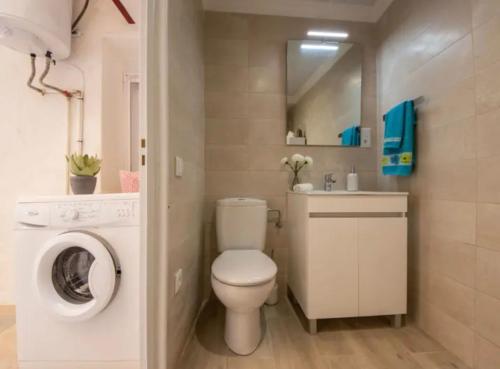 a bathroom with a toilet and a washing machine at Apt primera línea de mar in L'Ampolla