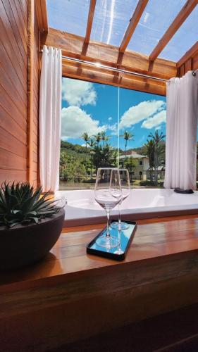 a wine glass sitting on a table in front of a window at Chale Vila dos Lagos in Venda Nova do Imigrante