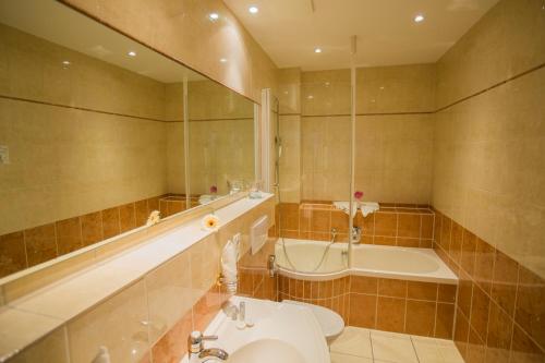 a bathroom with a tub and a toilet and a sink at Parkhotel Idar-Oberstein in Idar-Oberstein