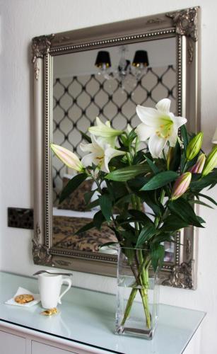 a vase of flowers on a table in front of a mirror at Tyndale B&B Torquay in Torquay