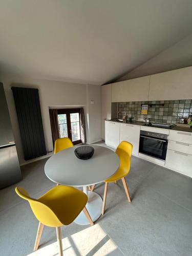 a kitchen with a white table and yellow chairs at Modern loft FREE PARKING, Old watermill in Montorio Veronese