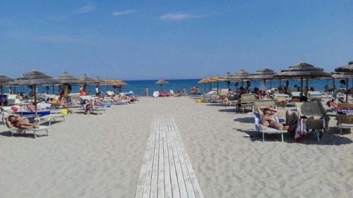 a beach with people sitting in chairs and umbrellas at Basilicata Host to Host - La Conchiglia in Metaponto