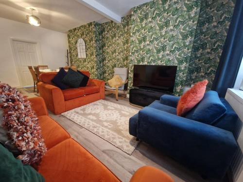 ein Wohnzimmer mit orangefarbenen Möbeln und einem Flachbild-TV in der Unterkunft SleepyStays 3 Bedroom Modern & Central Location in Merthyr Tydfil