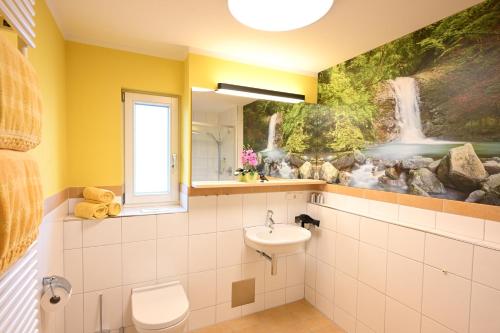 a bathroom with a waterfall mural on the wall at Familienurlaub Haus Bergahorn in Bolsterlang