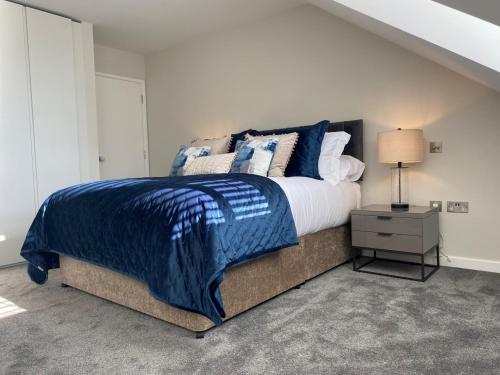 a bedroom with a bed with a blue blanket and a lamp at Hotel La Place in Saint Aubin