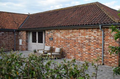 a brick building with two chairs and a door at Retreat East in Ipswich