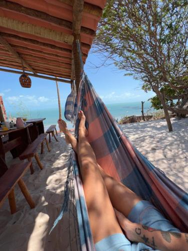 a woman laying in a hammock on the beach at Pousada Vila Matury in Icapuí