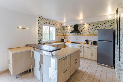 a kitchen with wooden cabinets and a black refrigerator at Le terminus in Villenauxe-la-Grande