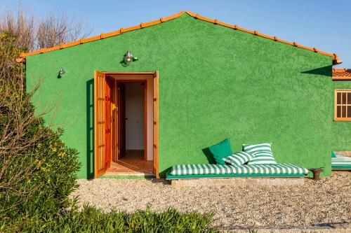 a green building with two chairs in front of it at Green Dunes House in Arcozelo