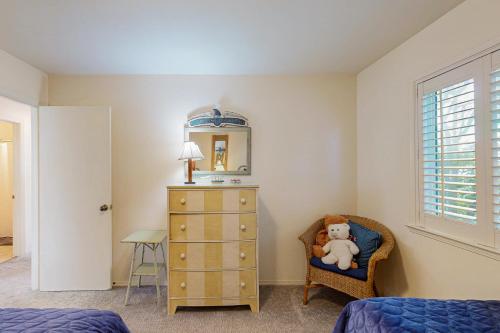 a bedroom with a dresser and a teddy bear in a chair at Oceanfront Delight in Cayucos