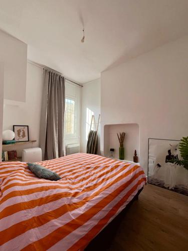 - une chambre dotée d'un lit avec une couverture rayée orange et blanche dans l'établissement Appartement T3 neuf centre historique, à Bordeaux