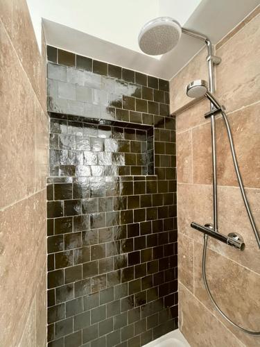 La salle de bains est pourvue d'une douche et d'un mur en carrelage brun. dans l'établissement Appartement T3 neuf centre historique, à Bordeaux