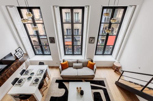 un salon avec un canapé et quelques fenêtres dans l'établissement Beautiful Loft Duplex 6P AC Heart of Marais, à Paris
