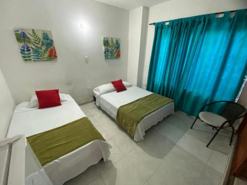 - 2 lits dans une chambre dotée de rideaux bleus dans l'établissement Paraíso en Bocagrande habitaciones, à Carthagène des Indes