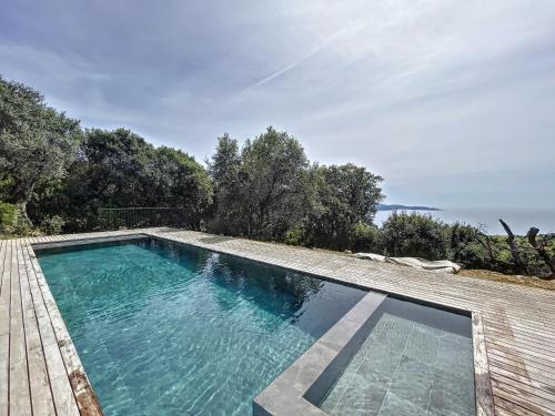 - une piscine sur une terrasse en bois avec l'océan en arrière-plan dans l'établissement Au parfum de la Myrte, à Olmeto