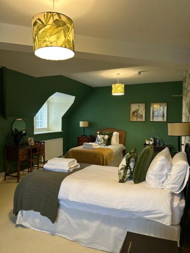 a bedroom with two beds and a green wall at Little Massingham Manor in Little Massingham