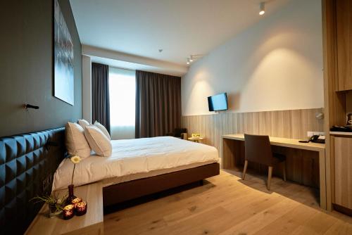 a hotel room with a bed and a desk with a computer at C-Hotels Westwing - ex Mercure in Roeselare