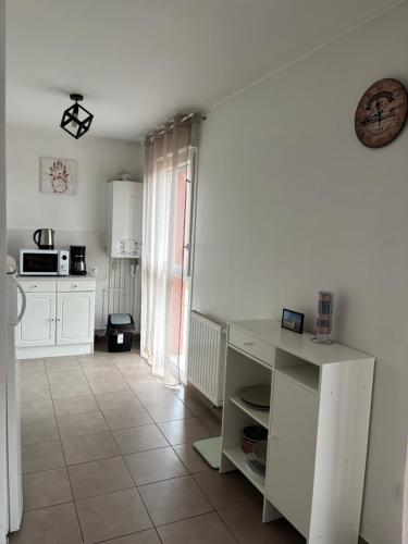 une cuisine avec des armoires blanches et un sol carrelé dans l'établissement Park Nevez - Lannion, à Lannion