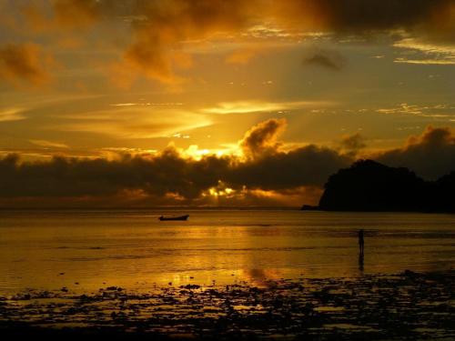 a boat in the ocean at sunset at Korovou Nature Lodge in Naviti Island
