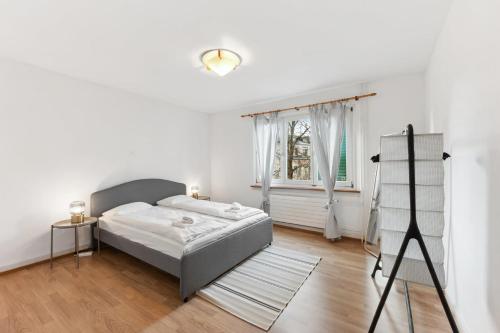 ein weißes Schlafzimmer mit einem Bett und einem Fenster in der Unterkunft Basic Apartment with Full Kitchen in Zürich