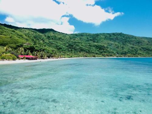 a view of a beach with a house in the distance at Korovou Nature Lodge in Naviti Island