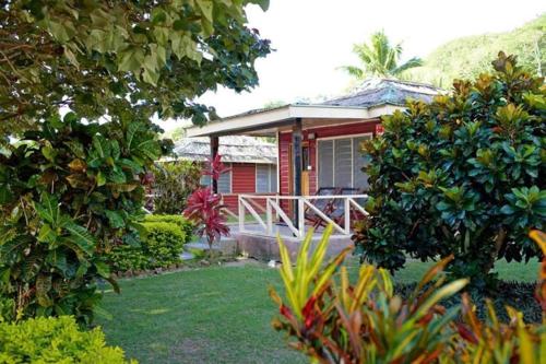 a red house with a porch in a yard at Korovou Nature Lodge in Naviti Island