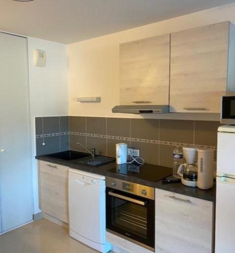 une cuisine avec un évier et une cuisinière four supérieur dans l'établissement Appartement tout confort climatisé, à Gruissan