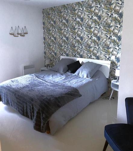 une chambre avec un grand lit et un mur dans l'établissement Appartement tout confort climatisé, à Gruissan