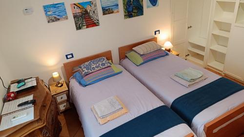 twee eenpersoonsbedden in een slaapkamer met twee lampen bij La Graziosa in Villa wifi parcheggio gratuito self check-in zona Lerici Guercio in Lerici