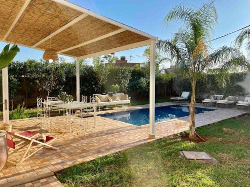 a pavilion with a table and chairs next to a pool at Villa Ambre with Pool And Garden in El Aggada