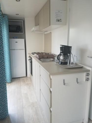 une cuisine blanche avec un évier et une cuisinière dans l'établissement Mobilhome premium 3 chambres, à Lit-et-Mixe
