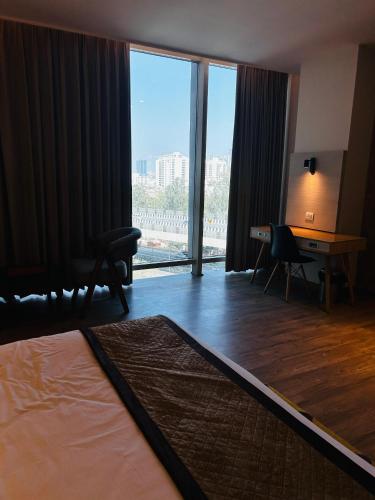 a hotel room with a desk and a large window at Hotel Sakura Gold in Gurgaon
