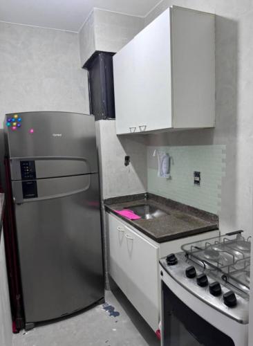 a kitchen with a stainless steel refrigerator and a stove at Sol e Mar 500 metros da praia in Vitória