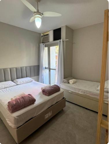 two beds in a room with a window at Sol e Mar 500 metros da praia in Vitória