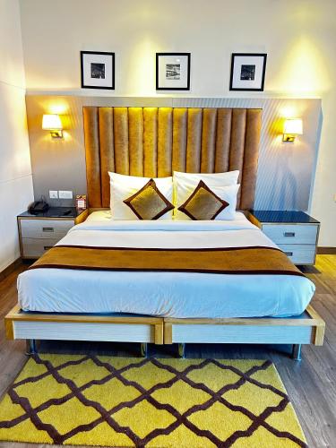 a bedroom with a large bed with a wooden headboard at Hotel Sakura Gold in Gurgaon