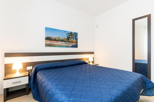 a bedroom with a blue bed and a desk and a mirror at Villaggio Sant' Andrea in Caorle