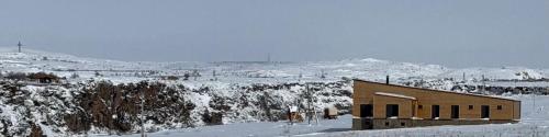 a building in the snow with snow covered mountains at Denver Villa in Sagmosavan