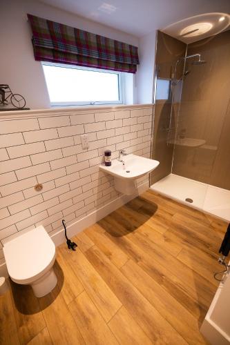 a bathroom with a sink and a toilet and a shower at Thistle Lodge in Comrie