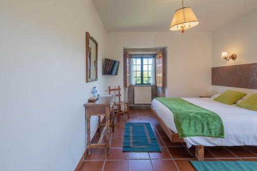 a bedroom with a bed and a desk and a window at Hotel Casa Rectoral in Tui