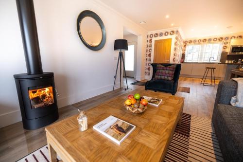 a living room with a fireplace and a table at Thistle Lodge in Comrie