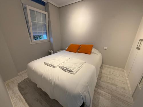 a bedroom with a white bed with an orange pillow at Maianca in Oleiros